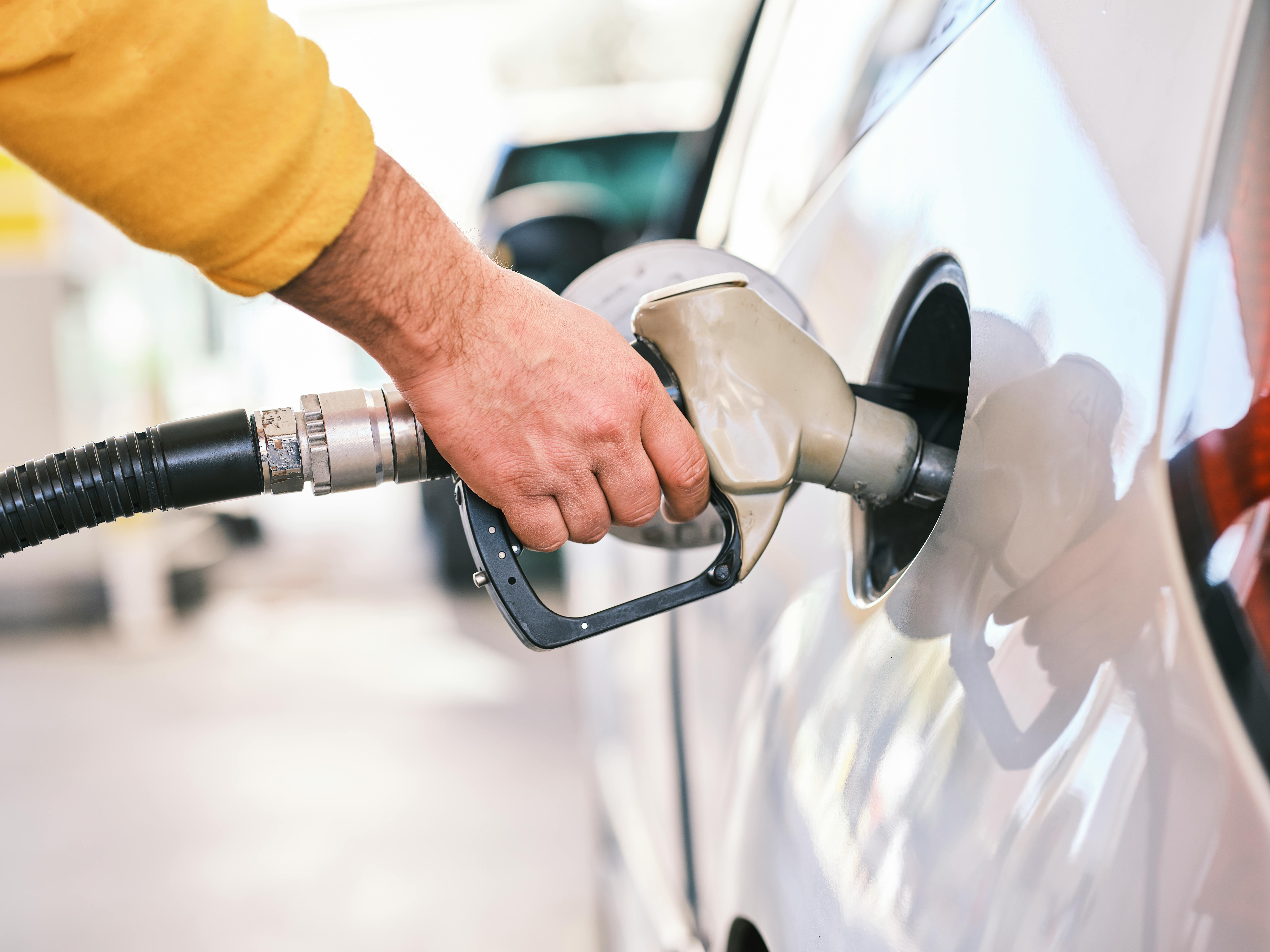 Close up of a person putting gas into a white vehicle