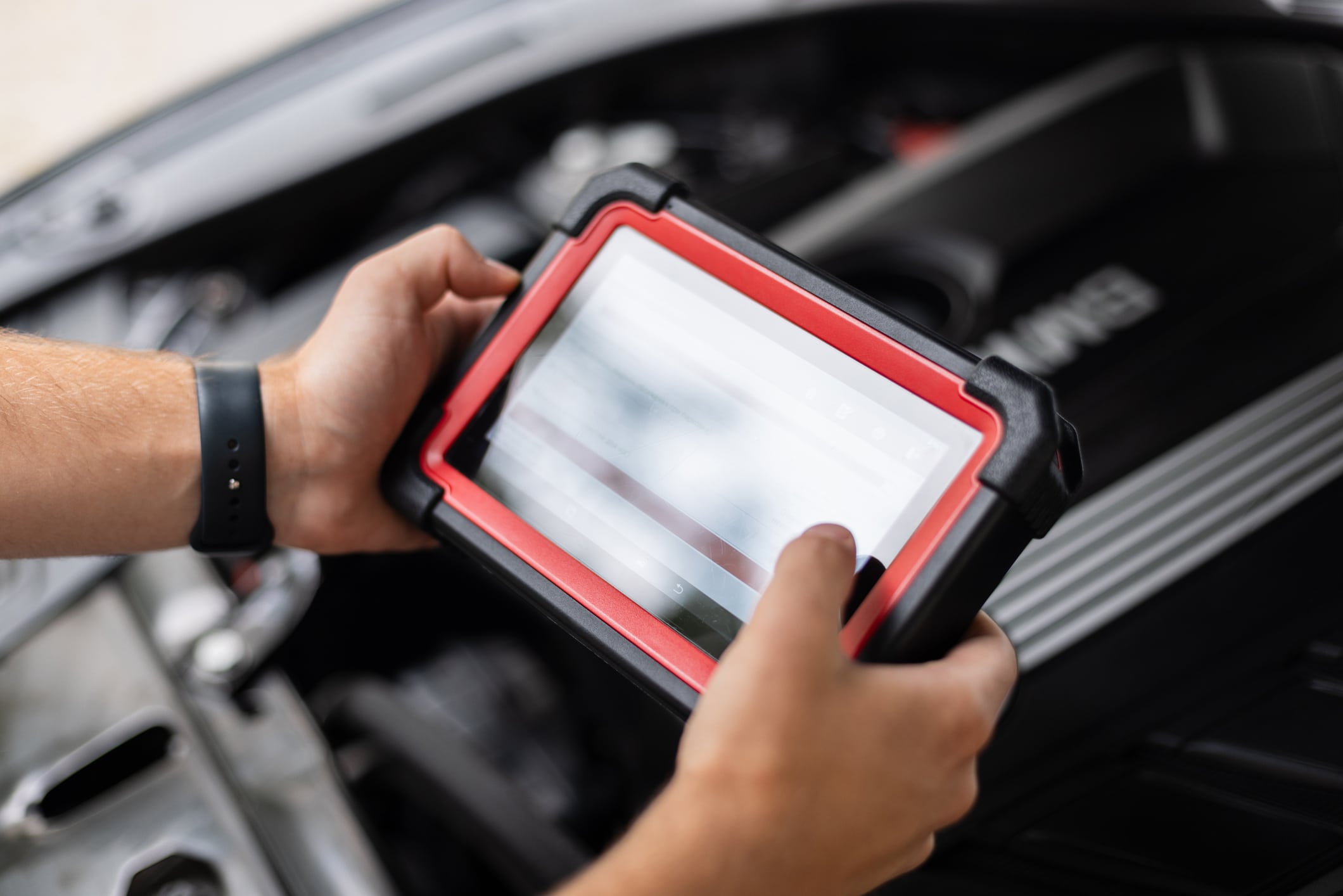 Close-up of a technician holding an advanced diagnostic device inside a car, performing system checks. Modern automobile maintenance and electronic diagnostics